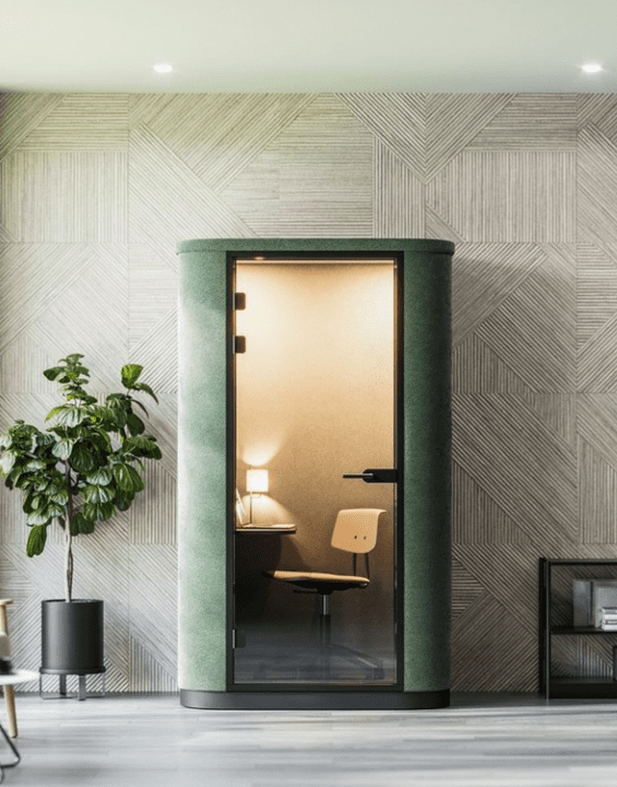 Individual office pod in phone booth style, upholstered in green fabric with internal furniture and lighting
