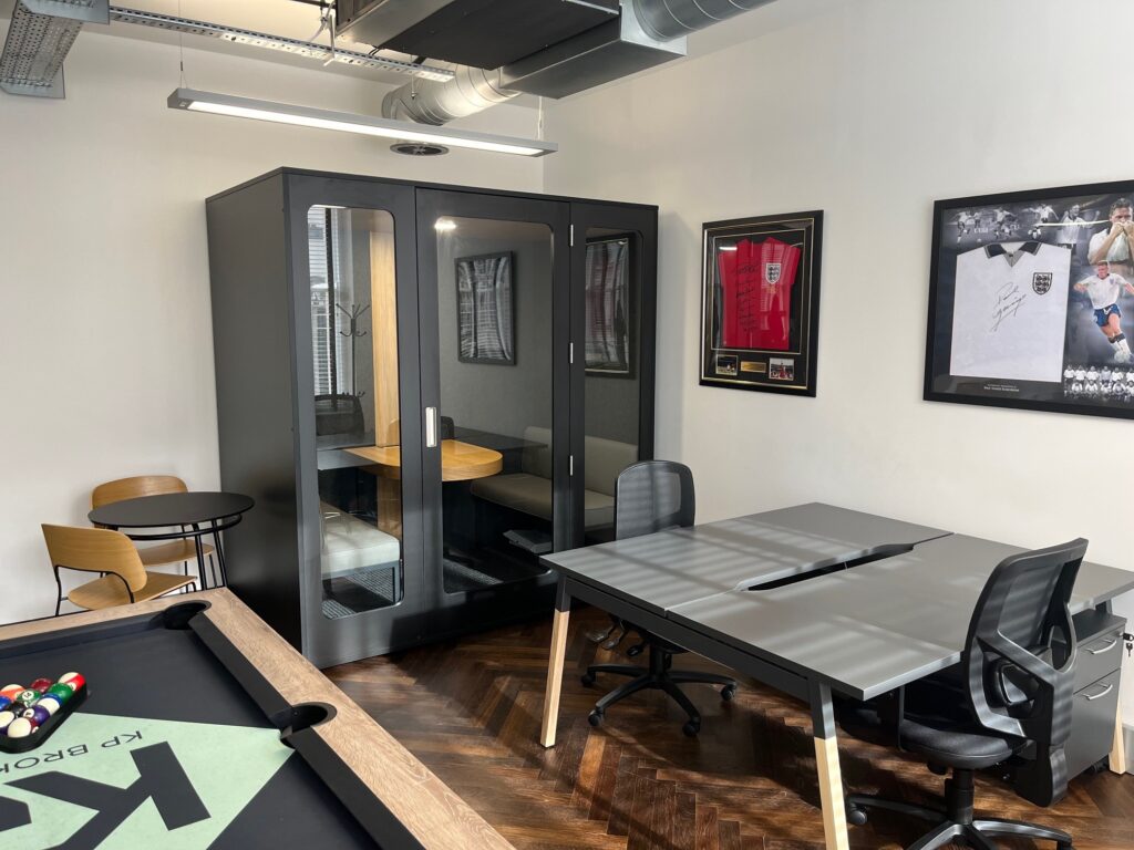 enclosed black meeting pod for four people with fixed interior furniture