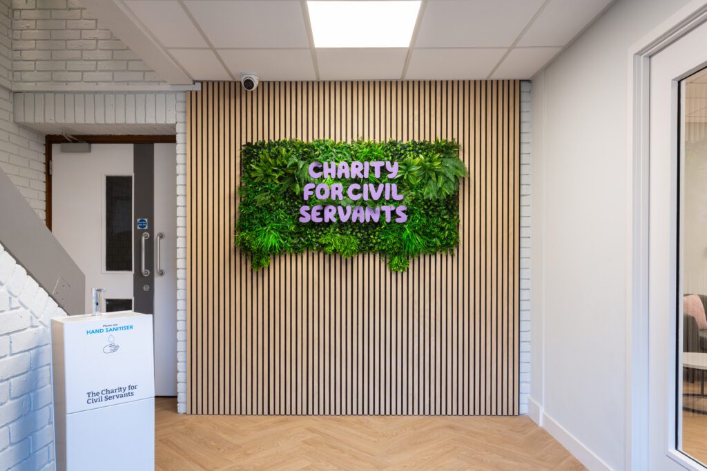 Artificial plants with brand signage against slat panelled wall