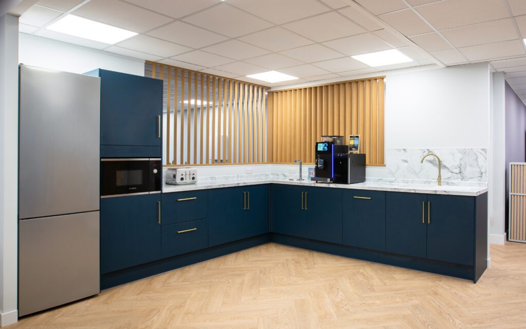 What's included in Office Design Services? A Beginner's Guide | Fusion Office Design Navy blue L-shaped kitchen in an office, with marble effect worktops