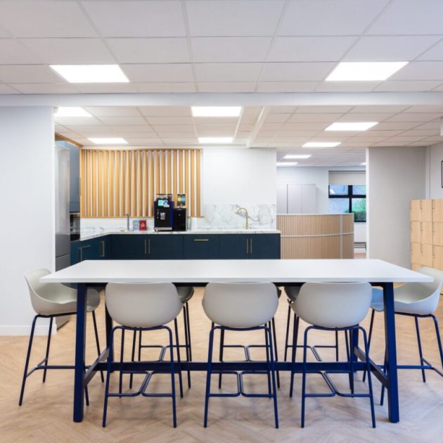Office kitchen and breakout space in Surrey, using white and navy as the feature colours within poseur height tables and kitchen units, with light oak flooring and woodwork